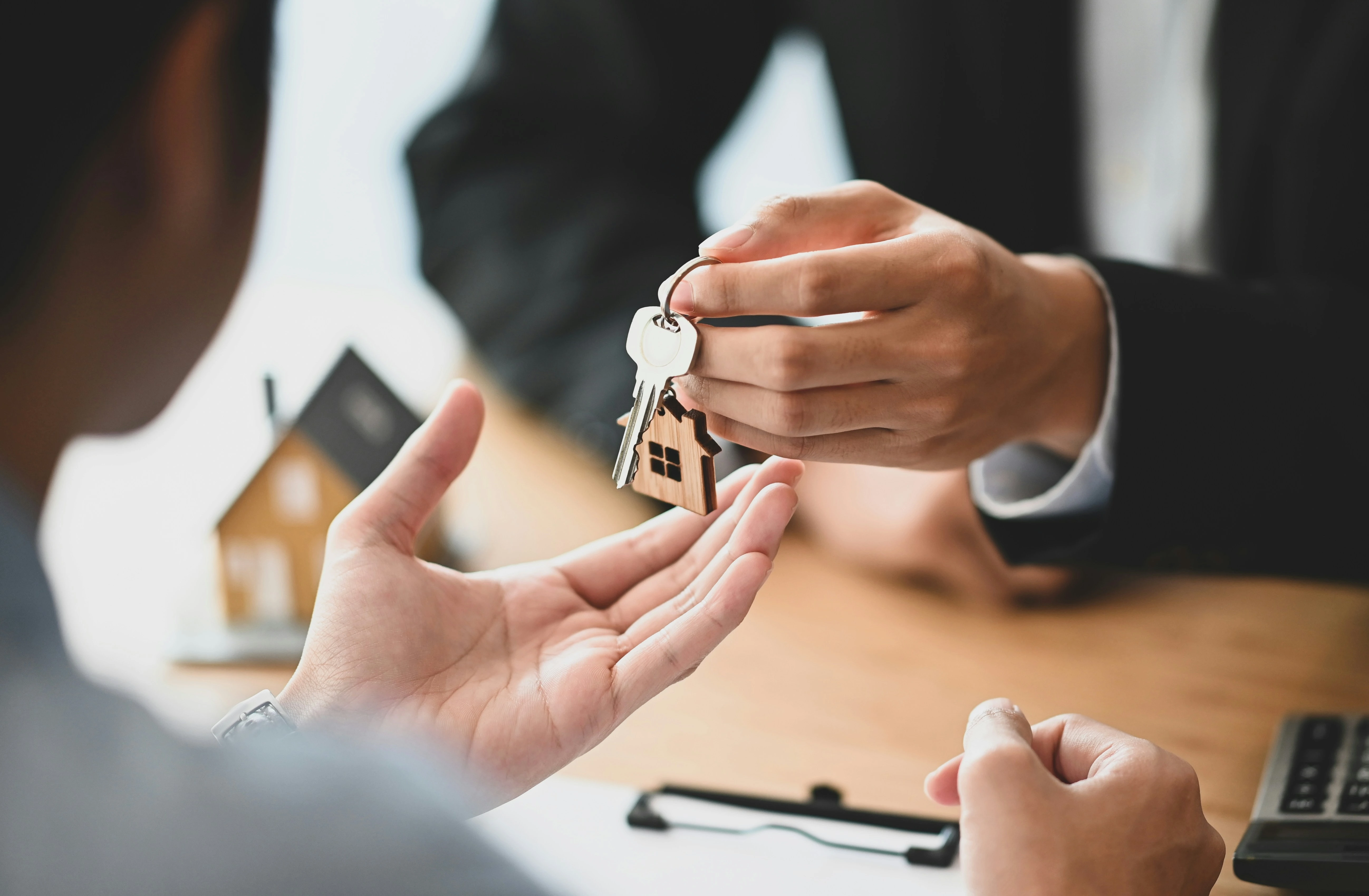 Black leather journal with silver steel disc binding resting on wooden shelf with machined steel pen.